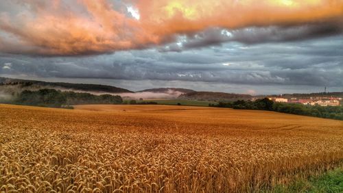 Scenic view of field against storm clouds