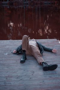 A man lies on a bridge against the background of a river