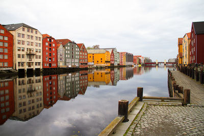 Buildings by river against sky in city