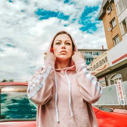 Portrait of young woman standing against building