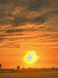 Scenic view of field against orange sky