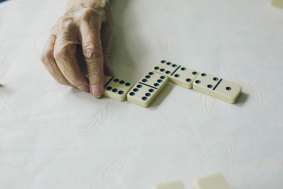 Cropped hand of person playing dominoes on white table