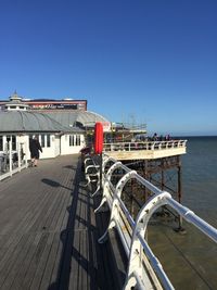 Built structure by sea against clear blue sky