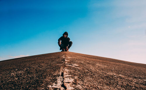 Low angle view of man on mountain against clear blue sky