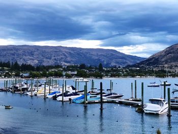 Boats moored at harbor against sky