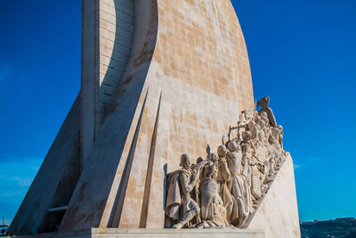 Low angle view of statues on building against blue sky