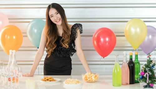 Young woman standing with balloon on table