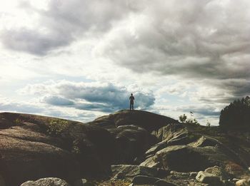 Rear view of man standing on mountain against sky