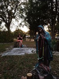 Full length of young woman sitting on tree