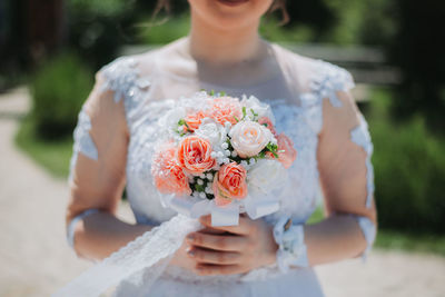 Midsection of bride holding bouquet