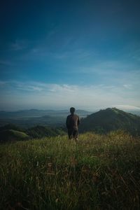 Rear view of man looking at field against sky