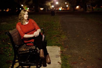 Portrait of woman sitting on bench at night