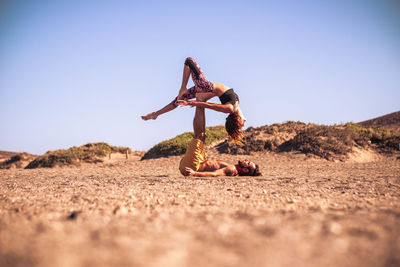 Full length of man and woman exercising outdoors against sky