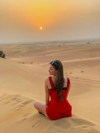 Young woman sitting on sand at desert