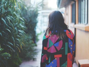 Rear view of woman in patterned clothing standing by building