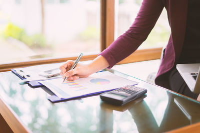 Midsection of woman holding paper with text on table