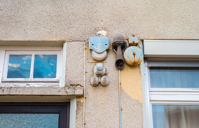 Low angle view of rusty bells mounted on building wall