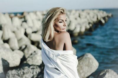 Portrait of young woman standing by sea