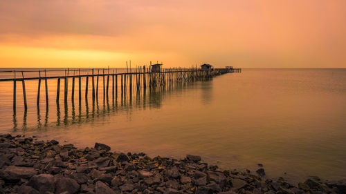 Pier over sea against sky during sunset