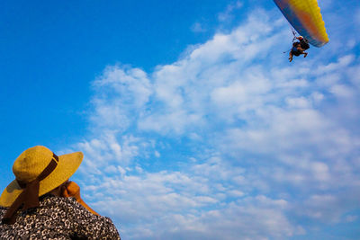 Rear view of woman looking at people paragliding against sky