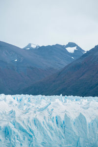 Glacier against snowcapped mountains and cloudy sky