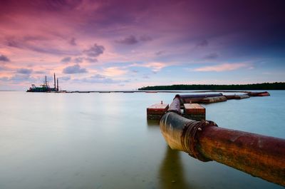 Pier over sea against sky during sunset