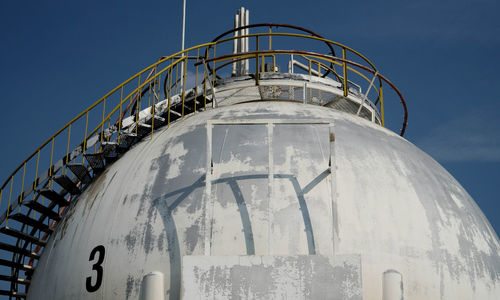 Storage tank at industry against sky