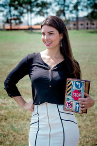 Portrait of a smiling young woman standing on field