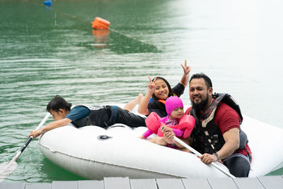 Father with children floating on inflatable ring over lake