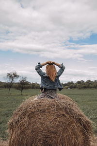 Rear view of man with arms raised on field against sky