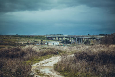 Arch bridge over field against sky