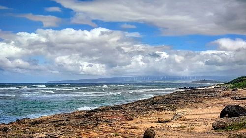 Scenic view of beach against cloudy sky