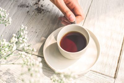 Midsection of person holding coffee cup on table
