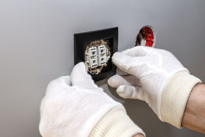 Close-up of hand holding bag against wall