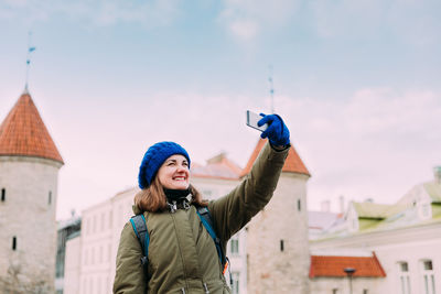 Rear view of woman with arms raised against sky