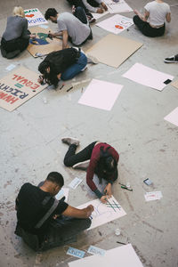 High angle view of female and male activist preparing signboard for social issues