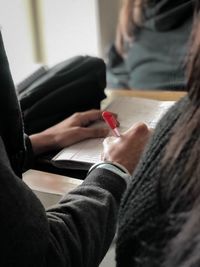 Cropped of person writing in book on table 