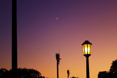 Illuminated street light against sky at sunset