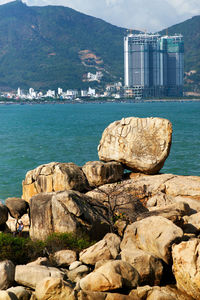 Rocks by sea against buildings in city