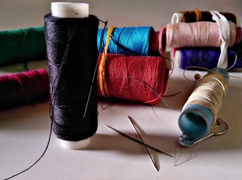 Close-up of multi colored spools with needles on table