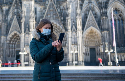 Young woman using phone while standing in city