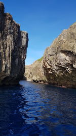 Rock formations in sea against clear blue sky