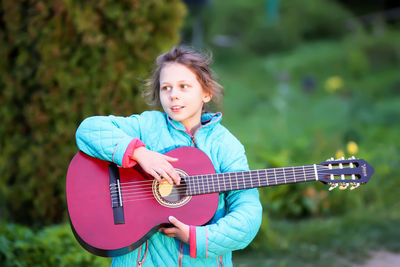 Cute girl playing guitar outdoors