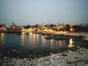 River by illuminated city against clear sky at night