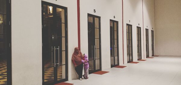 Rear view of woman walking by building