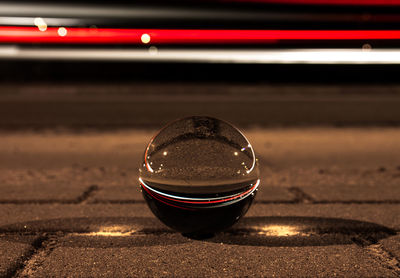 Close-up of crystal ball with light trails reflection on road