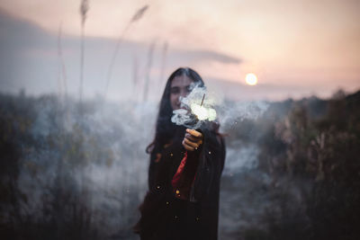 Full length of woman standing in snow against sky during sunset