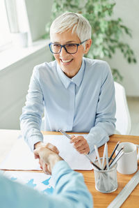 Smiling businesswoman shaking hand with colleague