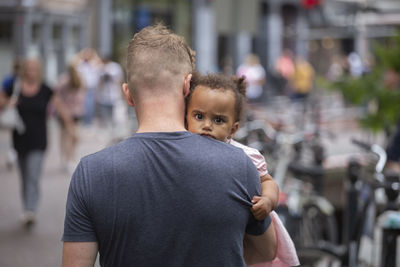 A young dad carrying his mixed race daughter in the city