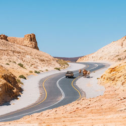 Road by mountain against clear blue sky